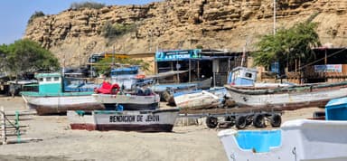Des bateaux colorés sur une plage avec des falaises en arrière-plan.
