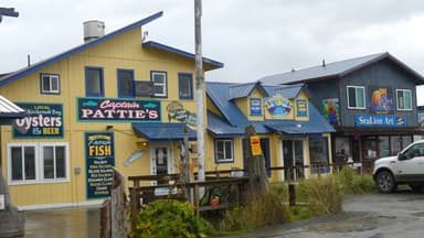 Un bâtiment coloré avec des enseignes de fruits de mer sous un ciel nuageux.