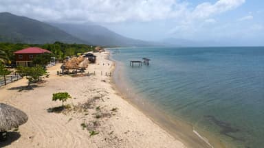Une plage tranquille avec des cabanes et des montagnes en arrière-plan.