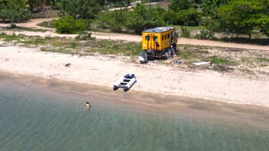 Un paysage de plage avec un bateau et un véhicule jaune.