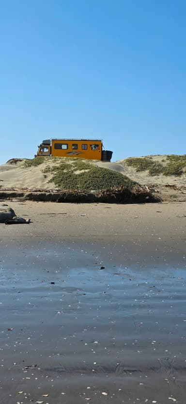 Un véhicule jaune sur une dune de sable au bord de la mer.
