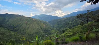 Une vue panoramique des montagnes verdoyantes sous un ciel nuageux.