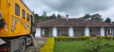Un bâtiment coloré avec un camion jaune devant dans un paysage verdoyant.