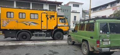 Deux véhicules stationnés dans une rue de Merida, au Venezuela, sous un ciel nuageux.
