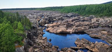 A scenic view of rocky terrain and a blue river surrounded by greenery.