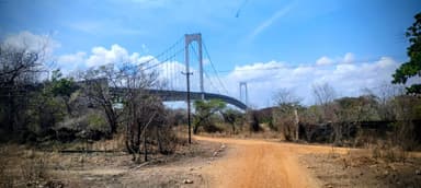 A bridge spans over a dry landscape under a blue sky.