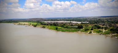 A scenic view of a river surrounded by green landscapes and clouds in the sky.