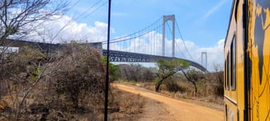 A bridge spans across a dry landscape under a blue sky.