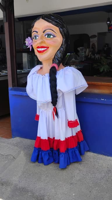 Une grande poupée colorée en costume traditionnel devant un bâtiment.