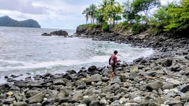 Un homme marche sur des rochers au bord de la mer.