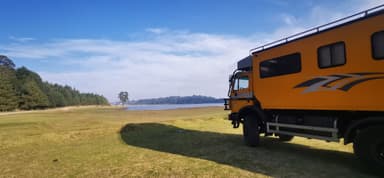 Un véhicule de voyage près d'un lac avec un ciel bleu.