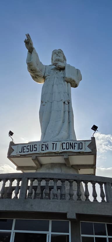 Une statue de Jésus avec un ciel bleu en arrière-plan.