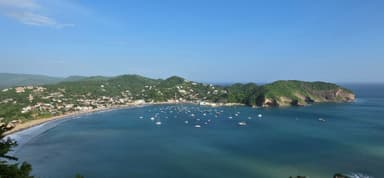 Une vue panoramique de la côte avec des bateaux dans l'eau et des collines verdoyantes.