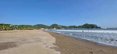Une plage avec des montagnes en arrière-plan et un ciel bleu.