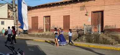 Des personnes marchent dans une rue avec des bâtiments colorés sous un ciel ensoleillé.