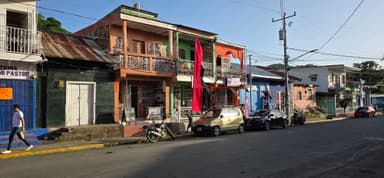 Des maisons colorées et des voitures sur une rue ensoleillée.