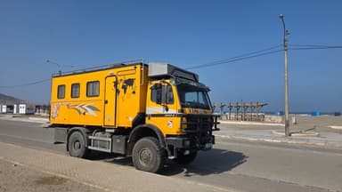 Un camion jaune garé sur une route près de la plage.