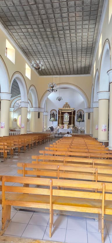Intérieur d'une église avec des bancs en bois et un autel au fond.
