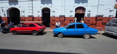 Deux voitures colorées garées sur une rue animée.