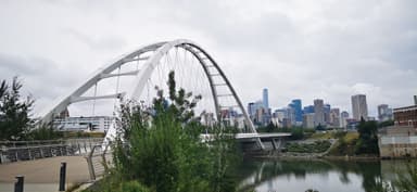 Un pont moderne avec des bâtiments en arrière-plan sous un ciel nuageux.