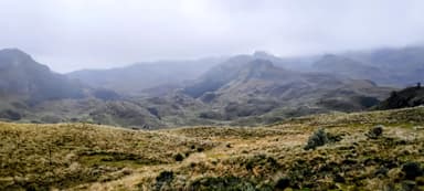 Un paysage montagneux brumeux avec des collines et des vallées.