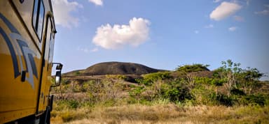 Un paysage de Bolivar avec une colline et un camion jaune.