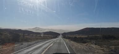 A scenic view of a winding road through hills under a clear blue sky.