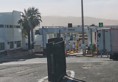 A border crossing with palm trees and signage in the background.