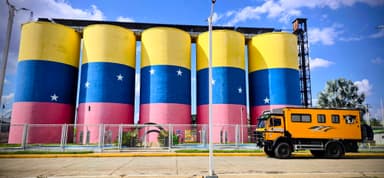 Des silos colorés avec un camion jaune devant, sous un ciel bleu.