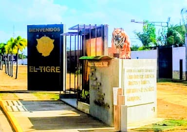 Une entrée avec un lion en pierre et un panneau de bienvenue à El Tigre.