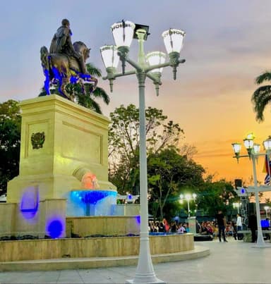 Une statue équestre au crépuscule avec des lampadaires et une fontaine.