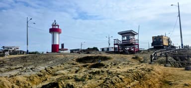 Un phare rouge et blanc sur une colline avec des bâtiments en arrière-plan.