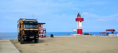 Un camion sur un terrain près d'un phare et de la mer.