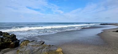 Une plage avec des vagues et des rochers sous un ciel bleu.