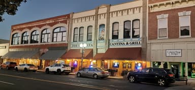 Une rue avec des bâtiments historiques et des restaurants éclairés au crépuscule.