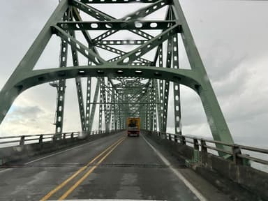 Un pont vert avec un camion sur la route sous un ciel nuageux.