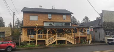 Un bâtiment en bois avec une terrasse et des plantes autour.