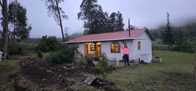 Une maison blanche avec un toit rouge et une personne à l'extérieur dans un paysage brumeux.