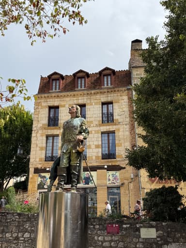Une statue en bronze devant un bâtiment en pierre à Dordogne.