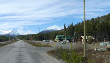 Une route avec des montagnes et des bâtiments en arrière-plan sous un ciel bleu.