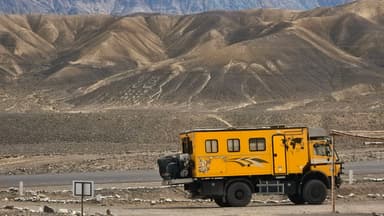 Un camion jaune devant des montagnes arides.