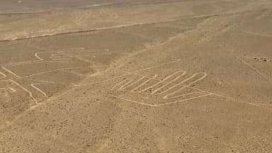 Des lignes géantes de mains dessinées sur le sol désertique.