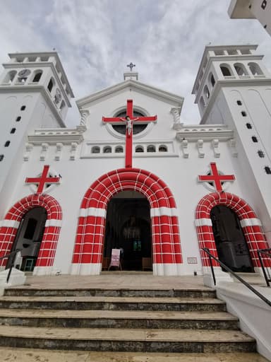 Une église blanche avec des croix rouges et un ciel nuageux.