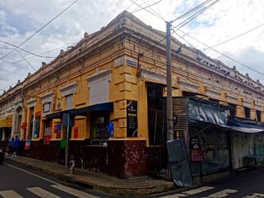 Un bâtiment ancien avec des murs jaunes et des fils électriques dans une rue.
