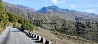 Une route sinueuse entourée de montagnes sous un ciel bleu.