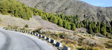Une route sinueuse entourée de montagnes et de forêts verdoyantes.