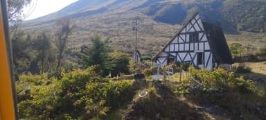 Une maison de style traditionnel entourée de verdure et de montagnes.
