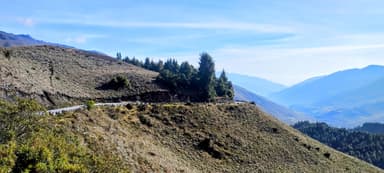 Une route sinueuse à travers des collines verdoyantes sous un ciel bleu.
