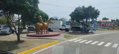 Une statue dorée d'un cavalier sur un cheval au milieu d'un rond-point.