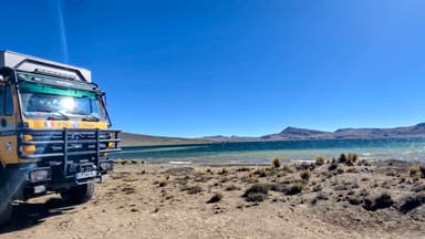 Un camion près d'un lac sous un ciel bleu.